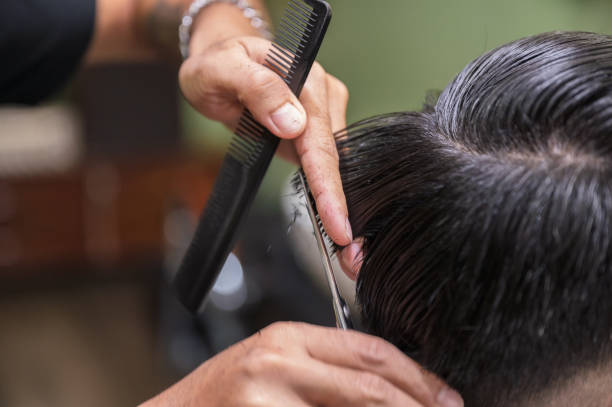 istock Barber cutting haircut the client hair with scissors and comb 1287639675