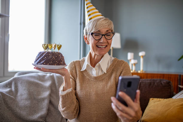 istock Senior woman holding a cake and having a virtual party 1287642757