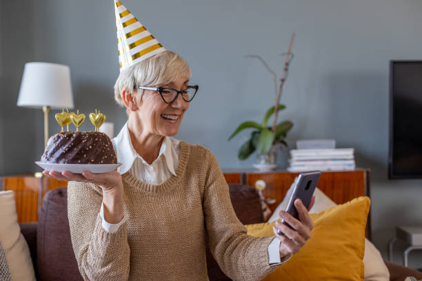 istock Senior woman holding a cake and having a virtual party 1287642926