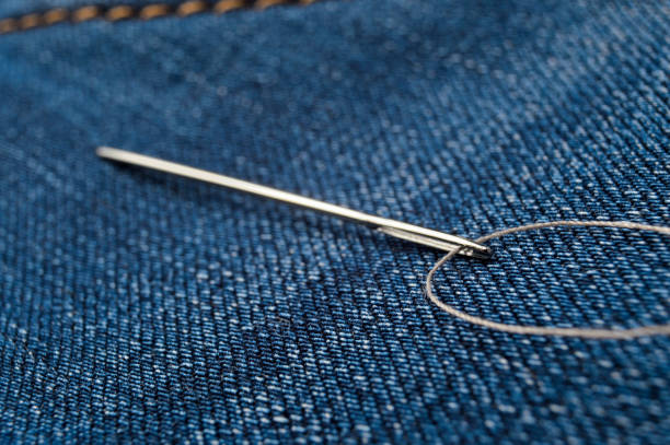 istock Close-up shot of needle with thread on jeans material. Close-up. 1287644291