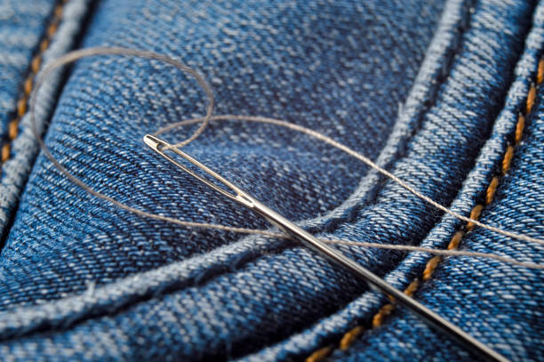 istock Close-up shot of needle with thread on jeans material. Close-up. 1287644584