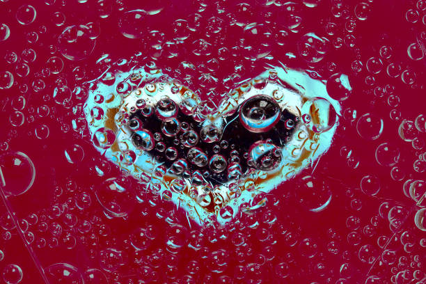 istock Multi-colored drops of water are located on a red-brown background with a black-white-blue silhouette of the hear.t. 1287645633