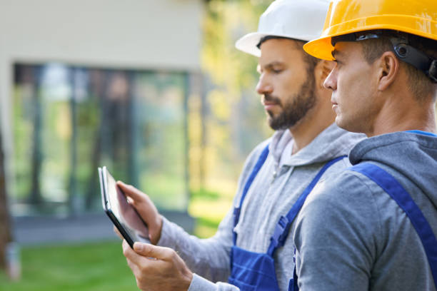 istock Close up of two young male builders using digital tablet pc, discussing ideas while working at cottage construction site 1287647365
