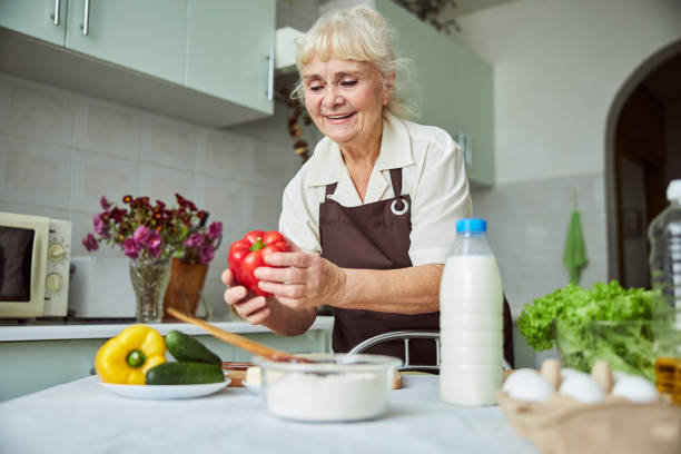 istock Joyful old woman cooking dinner at home 1287649293