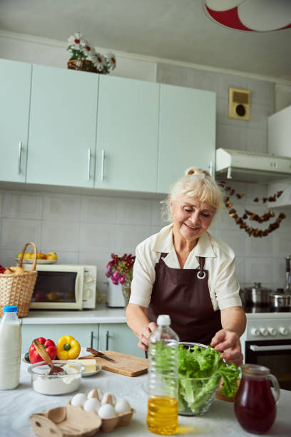 istock Lovely old lady cooking dinner in kitchen at home 1287649306