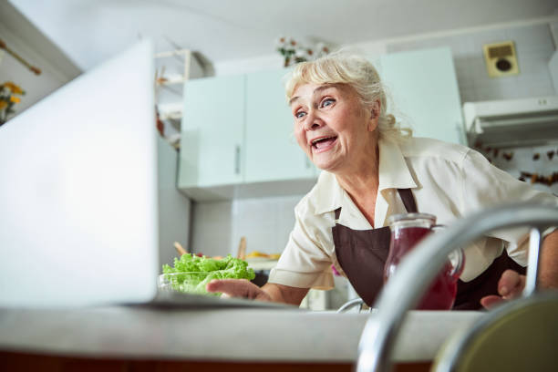 istock Cheerful elderly woman using modern laptop in kitchen 1287649307