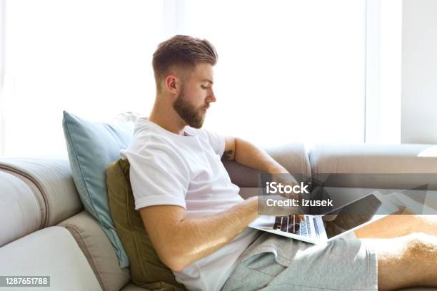 Young Man Using Laptop At Home Stock Photo - Download Image Now - 20-24 Years, Adult, Adults Only