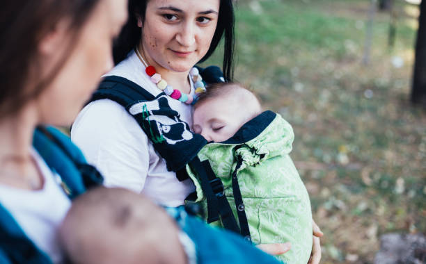 istock Young moms posing with babies in carriers 1287651822