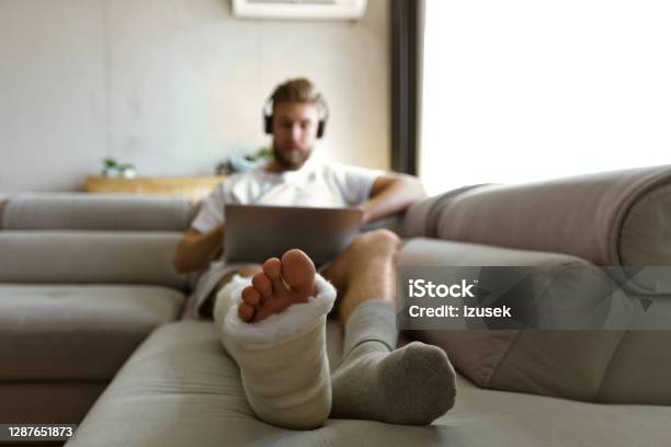 Young Man With Broken Leg During Video Call Stock Photo - Download Image Now - Orthopedic Cast, Broken Leg, Laptop