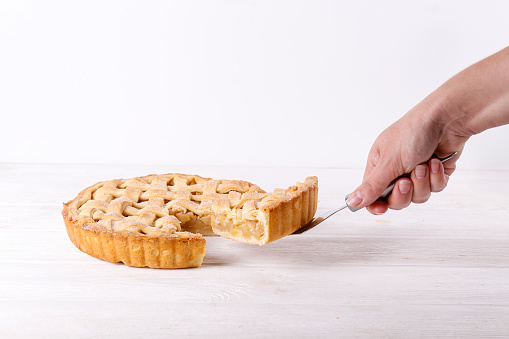 Woman cutting traditional American Thanks Giving lattice pie isolated on white background. Homemade fruit tart baked to golden crust. Close up, copy space, top view.