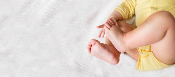barriga e pernas de bebê de seis meses de idade deitados na cama branca.  vista superior - newborn little girls baby lying down - fotografias e filmes do acervo