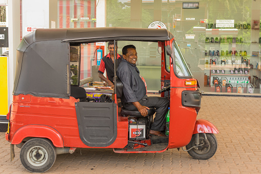 Kandy / Sri Lanka - April 30, 2015: Unidentified cheerful tuk-tuk driver at a gas station. Tuktuk taxis are a convenient and inexpensive form of transport.
