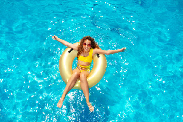 belle natation de fille dans la piscine sur le beignet gonflable - blue mattress vacations toy photos et images de collection