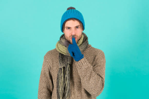 Keep my secret. Man handsome unshaven guy wear winter accessories on blue background. Winter season sale. Hipster knitted winter hat scarf and gloves. Emotional expression. Mysterious deal. Wish list. guarda mi secreto. hombre guapo hombre sin afeitar usar accesorios de invierno en el fondo azul. venta de temporada de invierno. pañuelo y guantes de sombrero de invierno de punto hipster. expresión emocional. un trato misterioso. lista de deseos