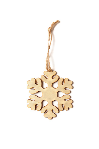 Wooden snowflake carved from wood with twine on a white background. Christmas decor and decorations