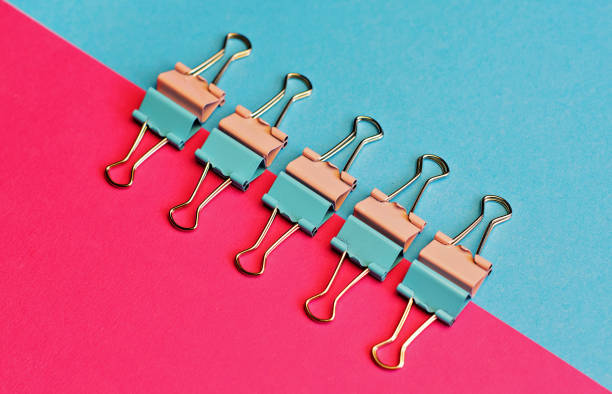 colored paper clips on two backgrounds in half-pink and blue. stationery - hands clasped business education cooperation imagens e fotografias de stock