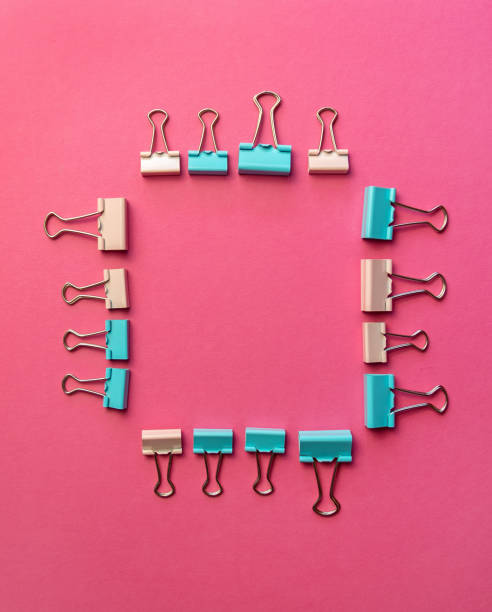 istock Colored paper clips on two backgrounds in half-pink and blue. Stationery 1287659037