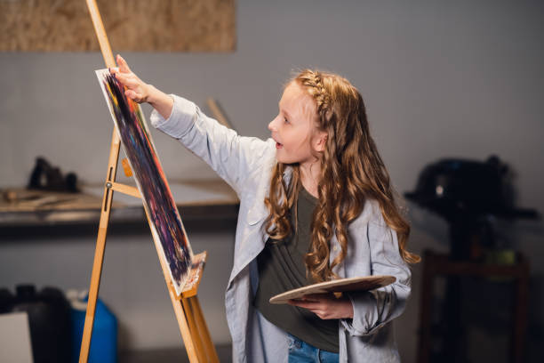 istock Young girl creative artist at work in a workshop. With passion draws a picture immersed in work 1287659559