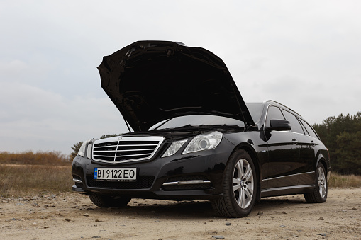 Dnipro, Ukraine - november 21, 2020: Mercedes-Benz E220 CDI 2011 black color in the autumn city near the forest