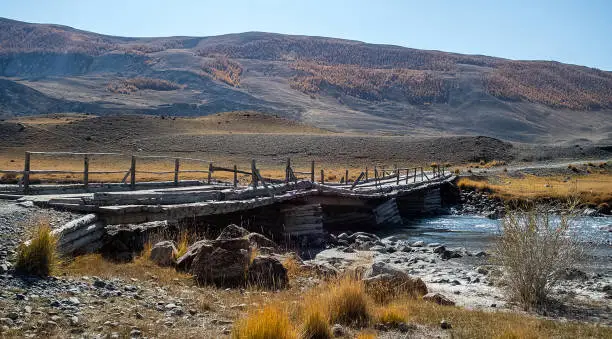 Photo of An old wooden bridge over a mountain river in Altai.
