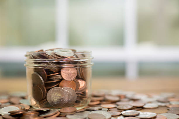 istock US coins overflow from glass jar. 1287667605