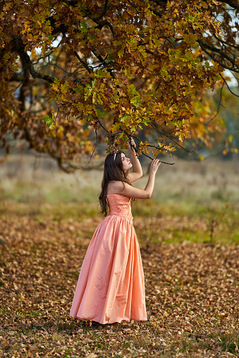 Autumnal beauty portrait of a young woman in an oak forest