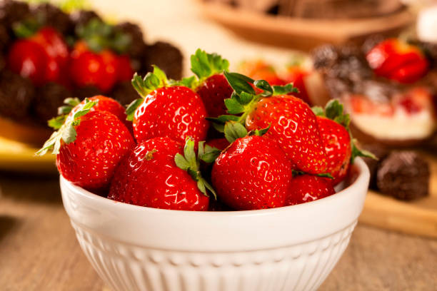 istock several strawberries in a white pot on a wooden table with easter egg background. 1287672502