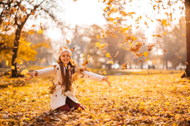 istock Girl throwing autumn leaves in park 1287673557