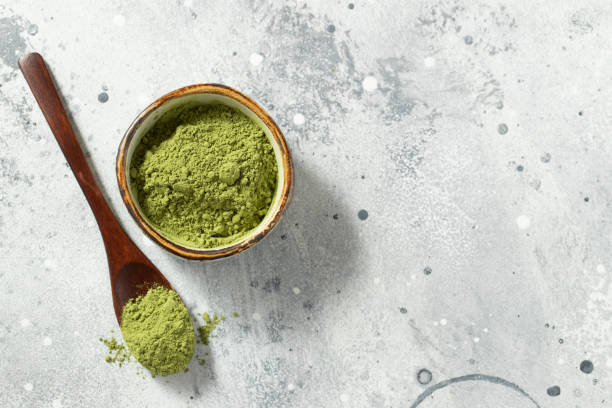 istock Green matcha tea powder with spoon on white concrete background. Top view with copy space 1287674597