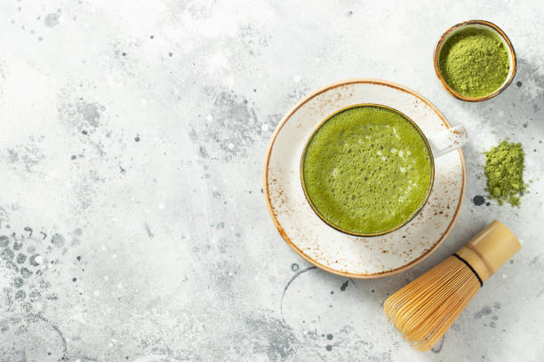 istock Matcha green tea latte in a cup with cream on a light concrete background. Top view with copy space 1287674601