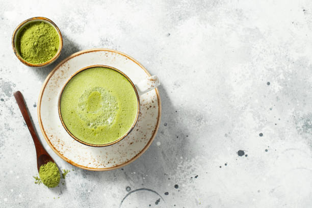 istock Matcha green tea latte in a cup with cream on a light concrete background. Top view with copy space 1287674610