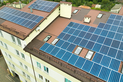 Aerial view of solar power plant with blue photovoltaic panels mounted of apartment building roof.