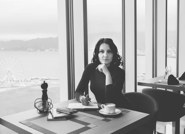 Elegant brunette woman sitting with coffee and notebook.