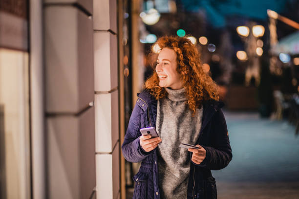 istock Young woman using mobile banking outdoors 1287685712