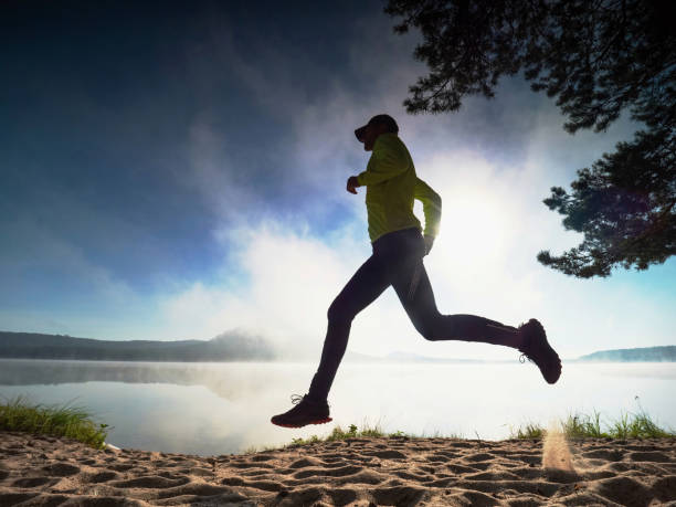 istock Tall slim runner on sandy bay along lake. Healthy  style 1287686069