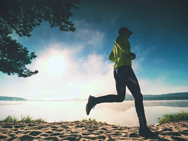 istock Sports man on the beach runs side by the sun, 1287686185
