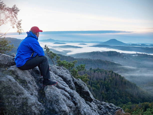 istock Man sit. Wonderful  view to heavy mist in deep valley 1287686262