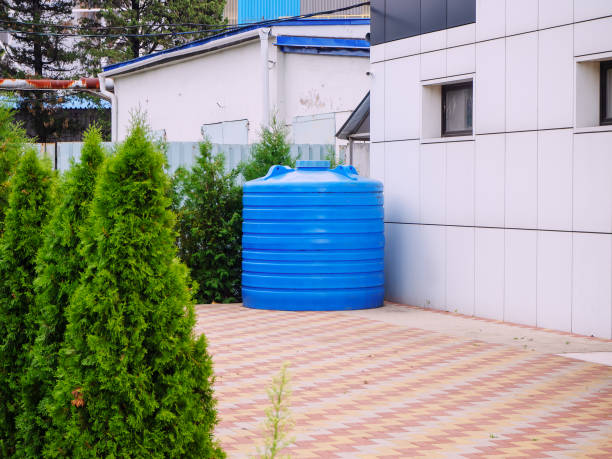 istock A blue plastic water tank stands in a backyard surrounded by thujas 1287689043
