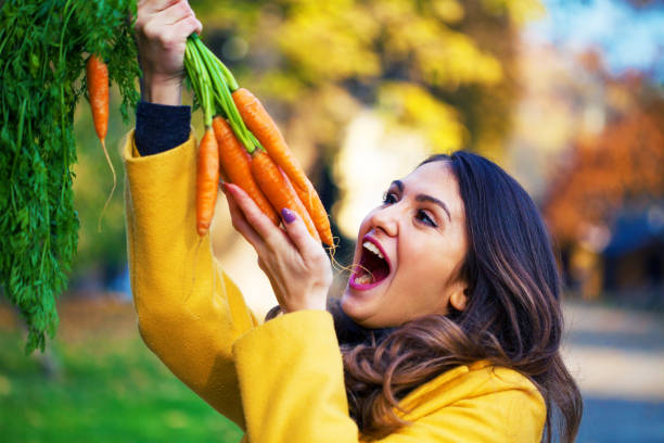istock Young woman eating carrots 1287693089