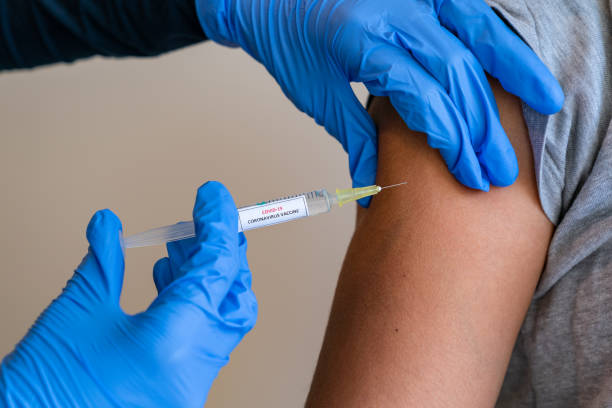 戴藍色乳膠手套的女醫生用針頭和注射器給兒童注射手臂，注射含有一劑covid-19疫苗的疫苗，通過免疫方式治癒 - 052 - covid 19疫苗 個照片及圖片檔