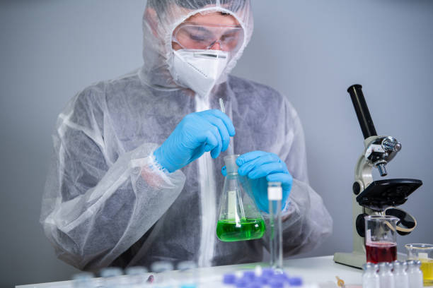Scientist shaking green fluid in beaker. Young laboratory assistant making test or research in lab. Technician testing chemistry lab experiment and shaking glass tube flask along with microscope. científico sacudiendo líquido verde en el vaso de precipitados. joven asistente de laboratorio haciendo pruebas o investigaciones en el laboratorio. el técnico que prueba el experimento del laboratorio de química y agita el matraz del tubo de vidrio de