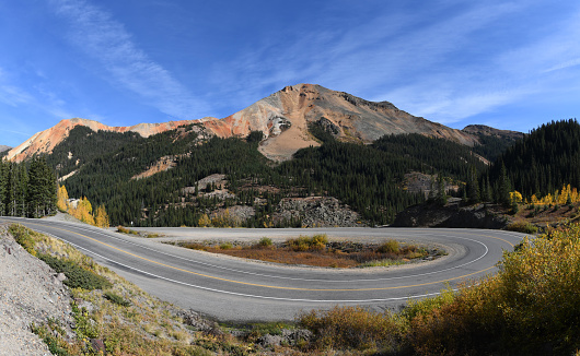 The Million Dollar Highway marked with a number of hairpin curves follows the route of U.S. 550 between Silverton and Ouray, Colorado. Scenic Red Mountain in the background. Picture taken in the fall from a roadside above the Uncompahgre Gorge towards the Red Mountain Pass.The original portion of the road was built  in 1883 to connect Ouray and Ironton, The Million Dollar Highway was completed in 1924.