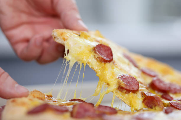 istock Man's hand holds a slice of pizza. 1287719022