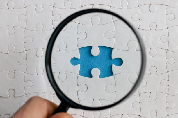 istock They look at white puzzles through a magnifying glass one is missing. 1287719036