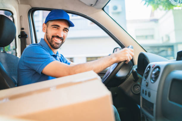 istock Delivery man driving van with cardboard boxes on seat. 1287723053