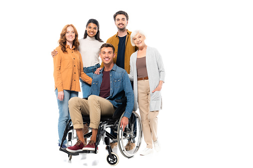 Multicultural friends hugging near smiling man in wheelchair isolated on white