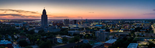 Lincoln, Nebraska at Twilight - Aerial Panorama Stitched panoramic shot of the Nebraska State Capitol and Downtown Lincoln from the air. nebraska stock pictures, royalty-free photos & images