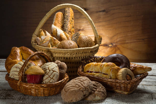 Mexican sweet bread basket Composition created with traditional Mexican breads, woven basket and wood background madalena stock pictures, royalty-free photos & images