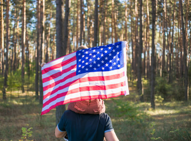 森の中でアメリカ国旗を持つ5歳の少年。憲法と愛国者の日。 - independence lifestyles smiling years ストックフォトと画像