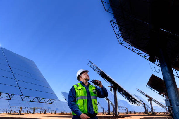 Solar power generation plant worker among reflective heliostats A worker at  the Khi Solar One solar energy generation plant in the desert near Keimoes in the Northern Cape, South Africa in front of heliostats reflecting heat to a generating tower. heliostat photos stock pictures, royalty-free photos & images